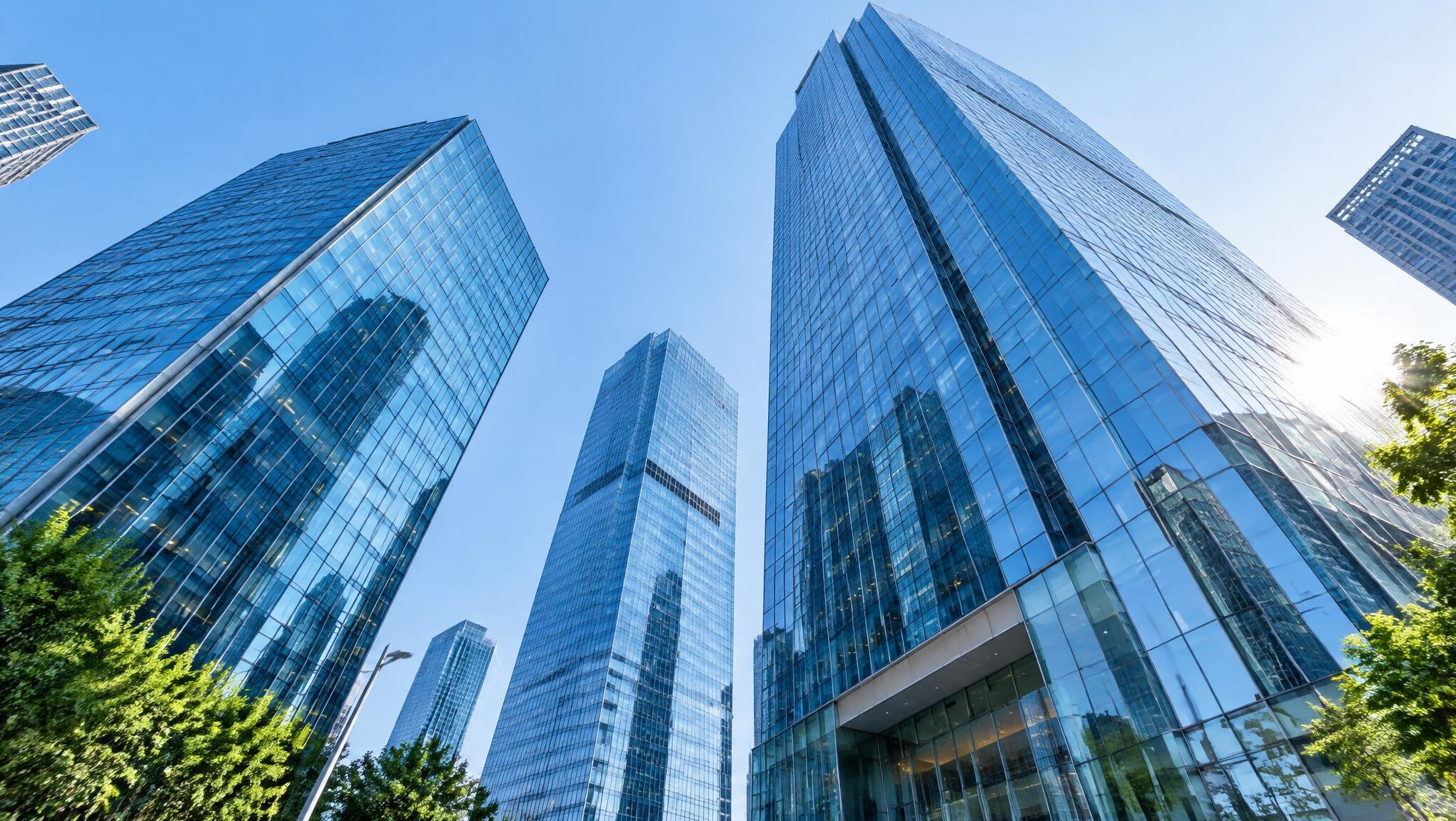 Glass office skyscrapers seen from below against a blue sky